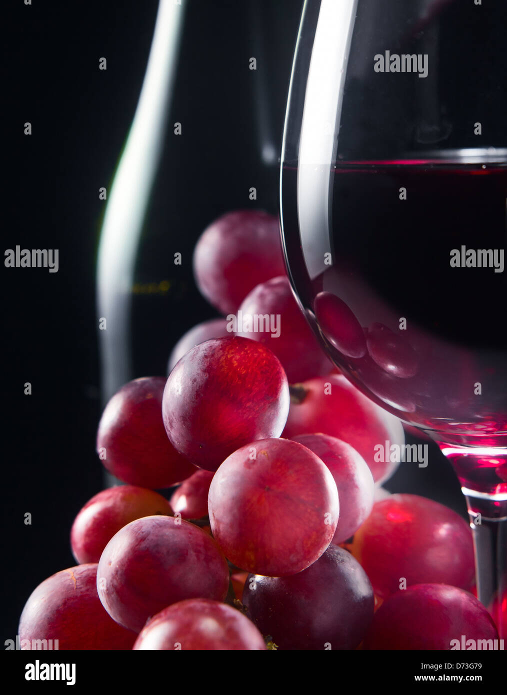 Traube und Glas mit Rotwein auf einem schwarzen Hintergrund Stockfoto