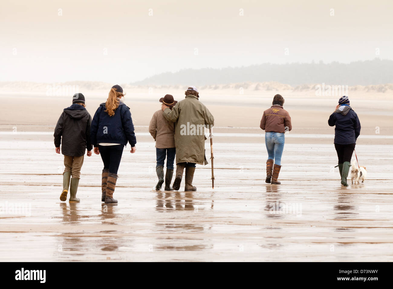 Eine Gruppe von Menschen zu Fuß am Strand, gesehen von hinten, Holkham Beach, North Norfolk, UK Stockfoto
