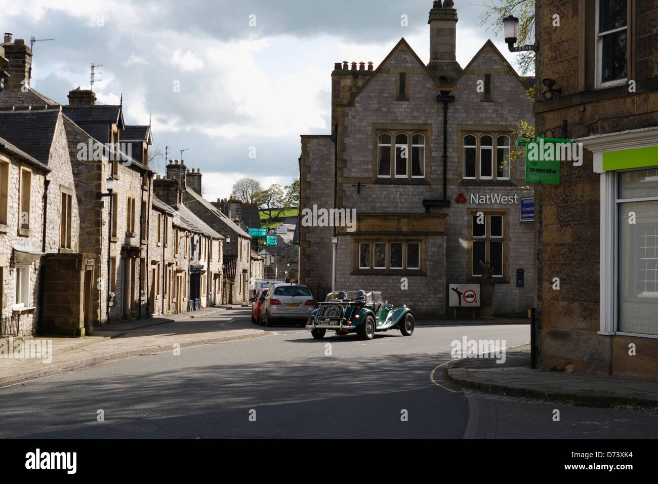 Ein Auto mit offenem Oberdeck fährt durch das Dorf Tideswell Derbyshire England Großbritannien im Peak District Nationalpark Rural Britain Stockfoto