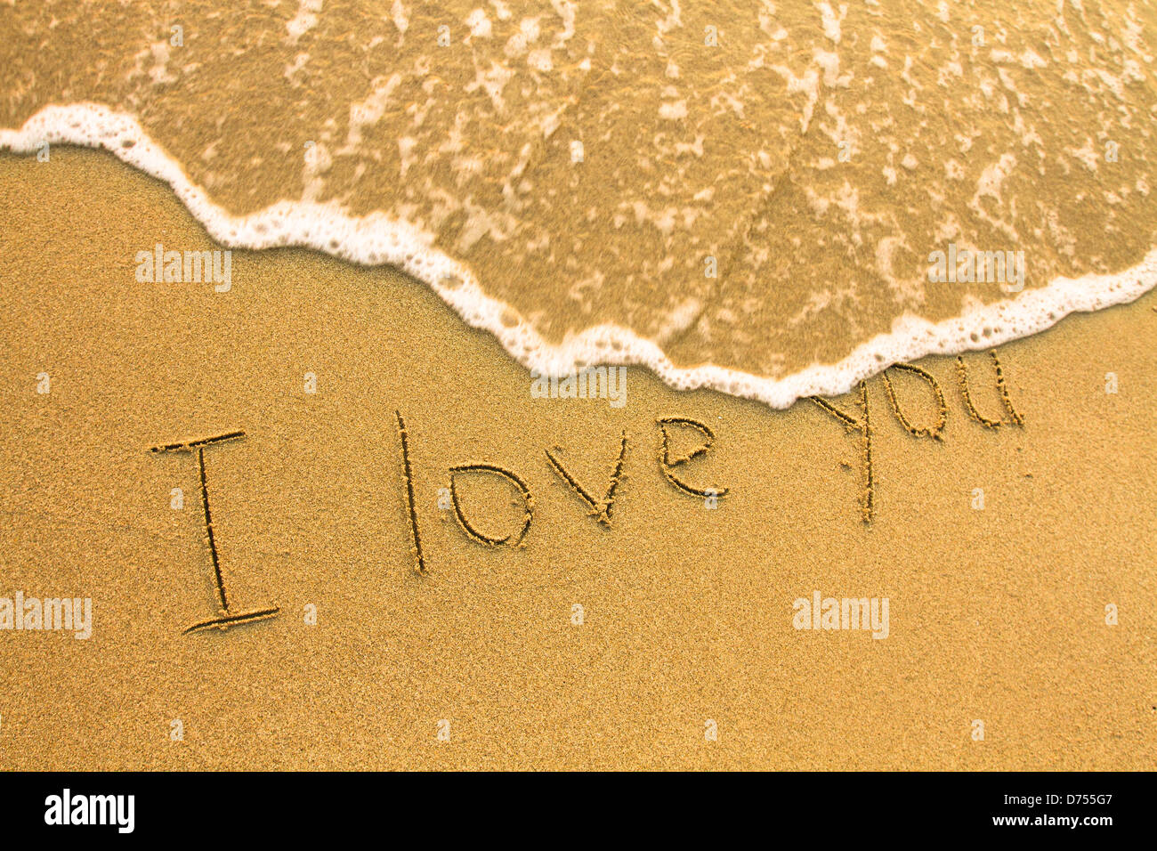 Ich liebe dich - Inschrift auf dem Strandsand, weiche Surfwelle. Stockfoto
