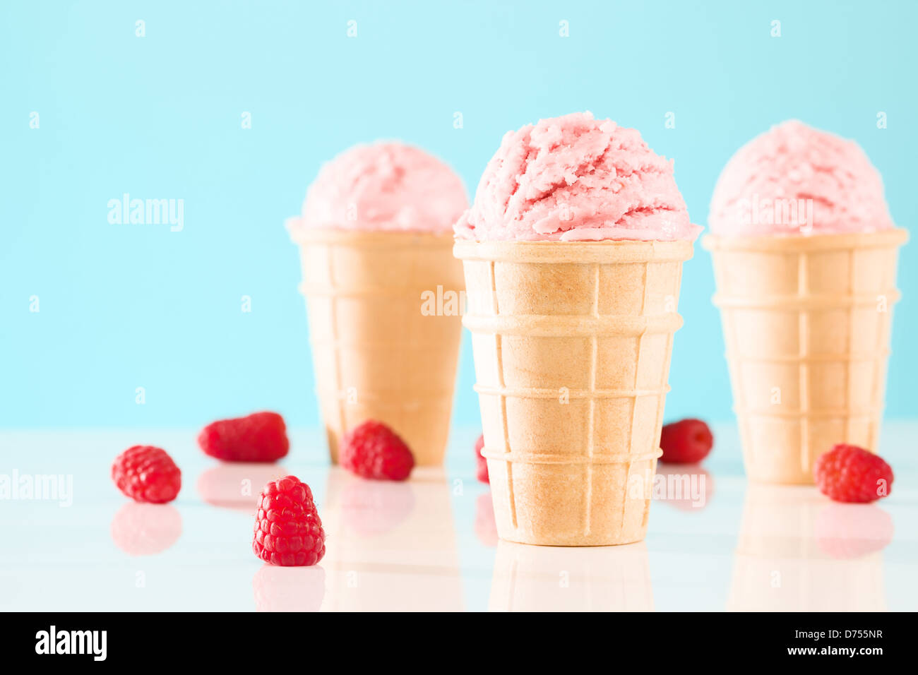 drei Himbeer Eis Kegel mit blauem Hintergrund Stockfoto