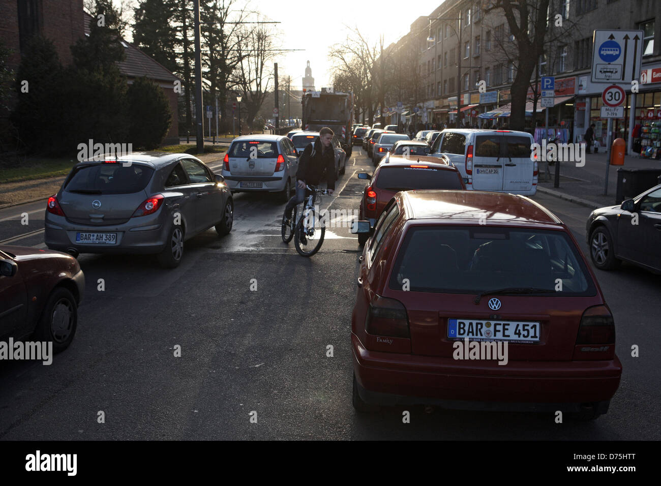 Berlin, Deutschland, fährt Radfahrer entgegen der Fahrtrichtung zwischen stationären Autos im Stau durch Stockfoto