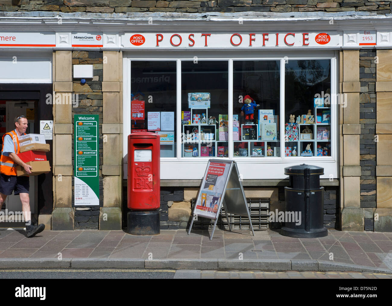 Briefträger mit Paketen aus Postamt, Stadt Windermere, Lake District National Park, Cumbria, England UK Stockfoto