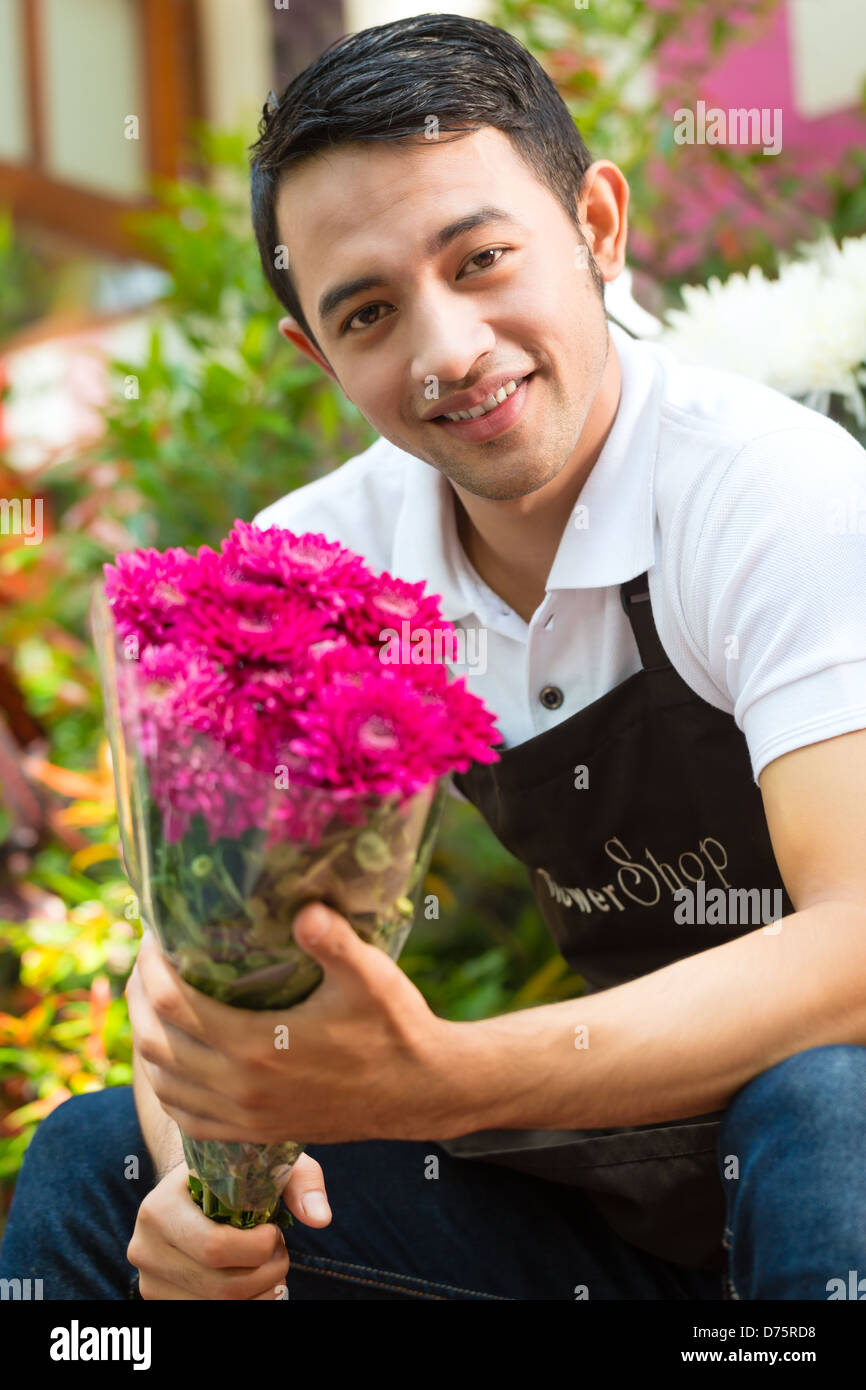 Freundliche asiatische Florist oder Verkäufer in einem Blumenladen mit einem Blumenstrauß Stockfoto