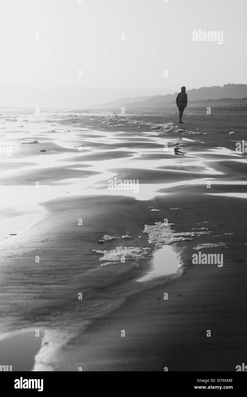 Einsame Person an einem Winter-Strand, schwarz / weiß Bild Stockfoto