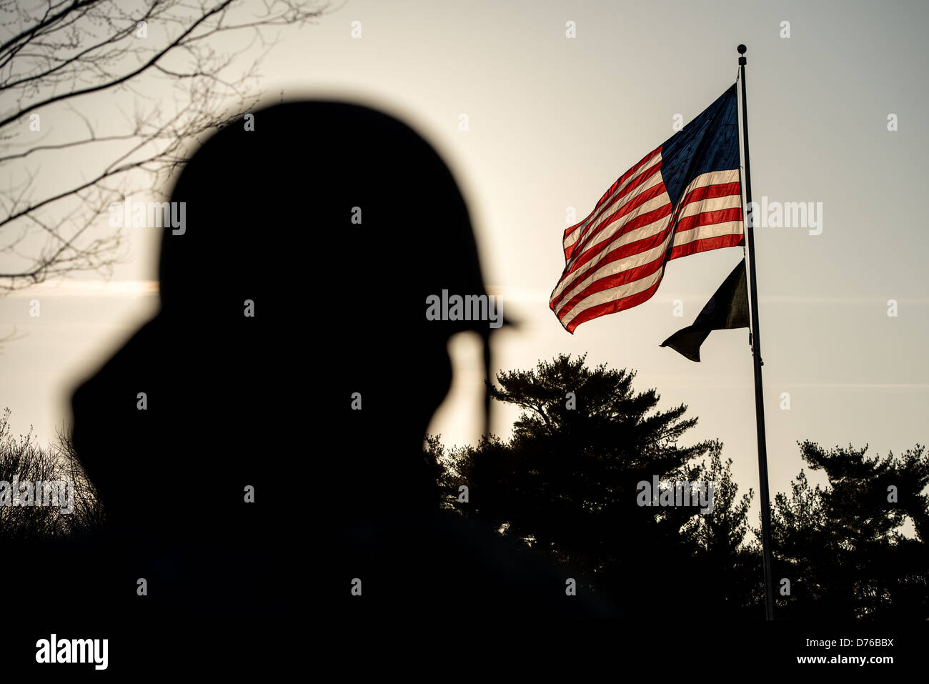 Korean war Veterans Memorial American Flag Washington DC // WASHINGTON DC – die amerikanische Flagge und die Kriegsgefangenenfahne fliegen am Korean war Veterans Memorial in Washington DC hinterleuchtet von der Sonne. Die Silhouette des Helms und des Kopfes einer Soldatenstatue ist im Vordergrund zu sehen. Ein Teil der 19 Edelstahlstatuen der Gedenkstätte repräsentiert eine Streifeneinheit. Das 1995 geweihte Denkmal ehrt die 5,8 Millionen Amerikaner, die während des Koreakrieges (1950–1953) in den US-Streitkräften gedient haben. Das Hotel befindet sich in der National Mall in der Nähe des Lincoln Memorial und verfügt über eine reflektierende Wand und einen Pool of R Stockfoto