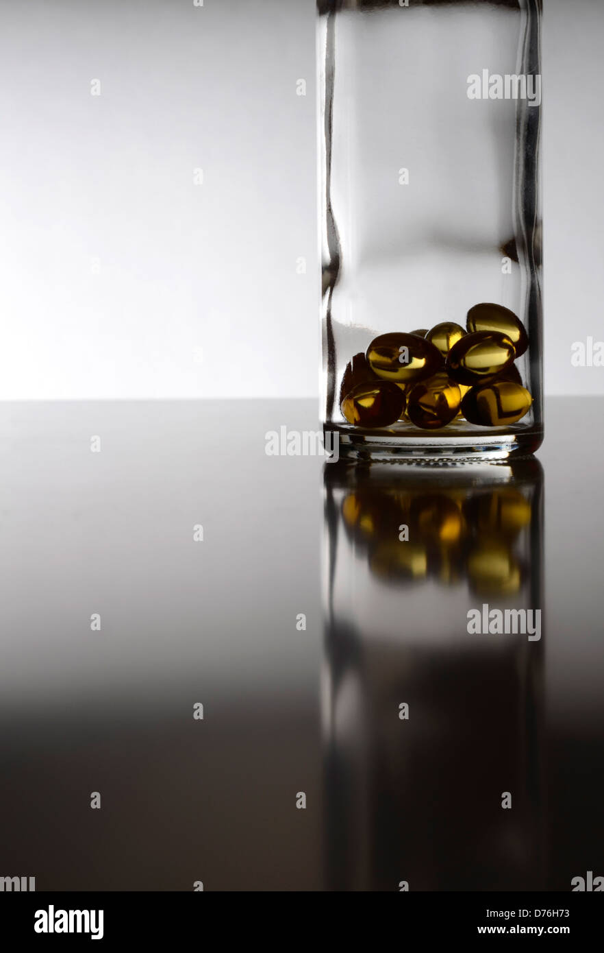 Goldene Kapseln in einer Glasflasche Stockfoto