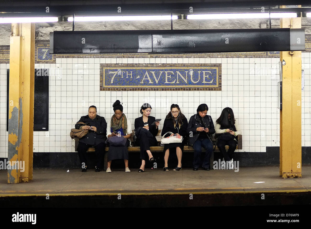 Passagiere warten auf einen Zug auf der Plattform der u-Bahnstation 7th Avenue in Brooklyn, New York City. Stockfoto