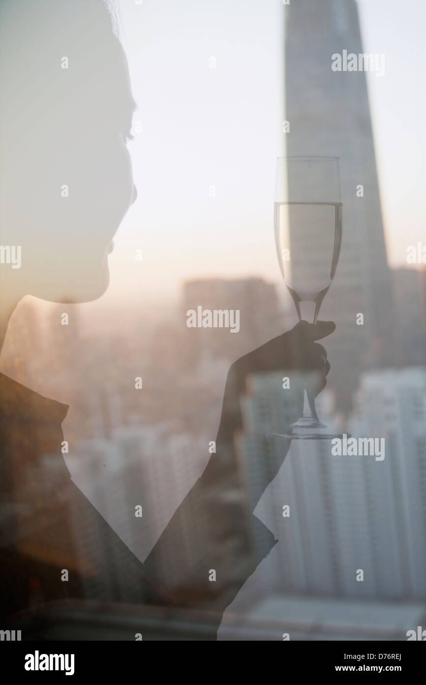 Doppelbelichtung Frau Toasten mit Champagnerglas über Stadtbild Stockfoto