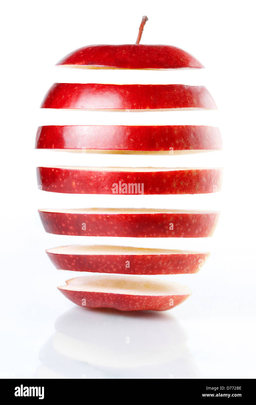 Scheiben von rotem Apfel hängen in der Luft isoliert auf weißem Hintergrund. Genetische Technik Essenskonzept. Stockfoto