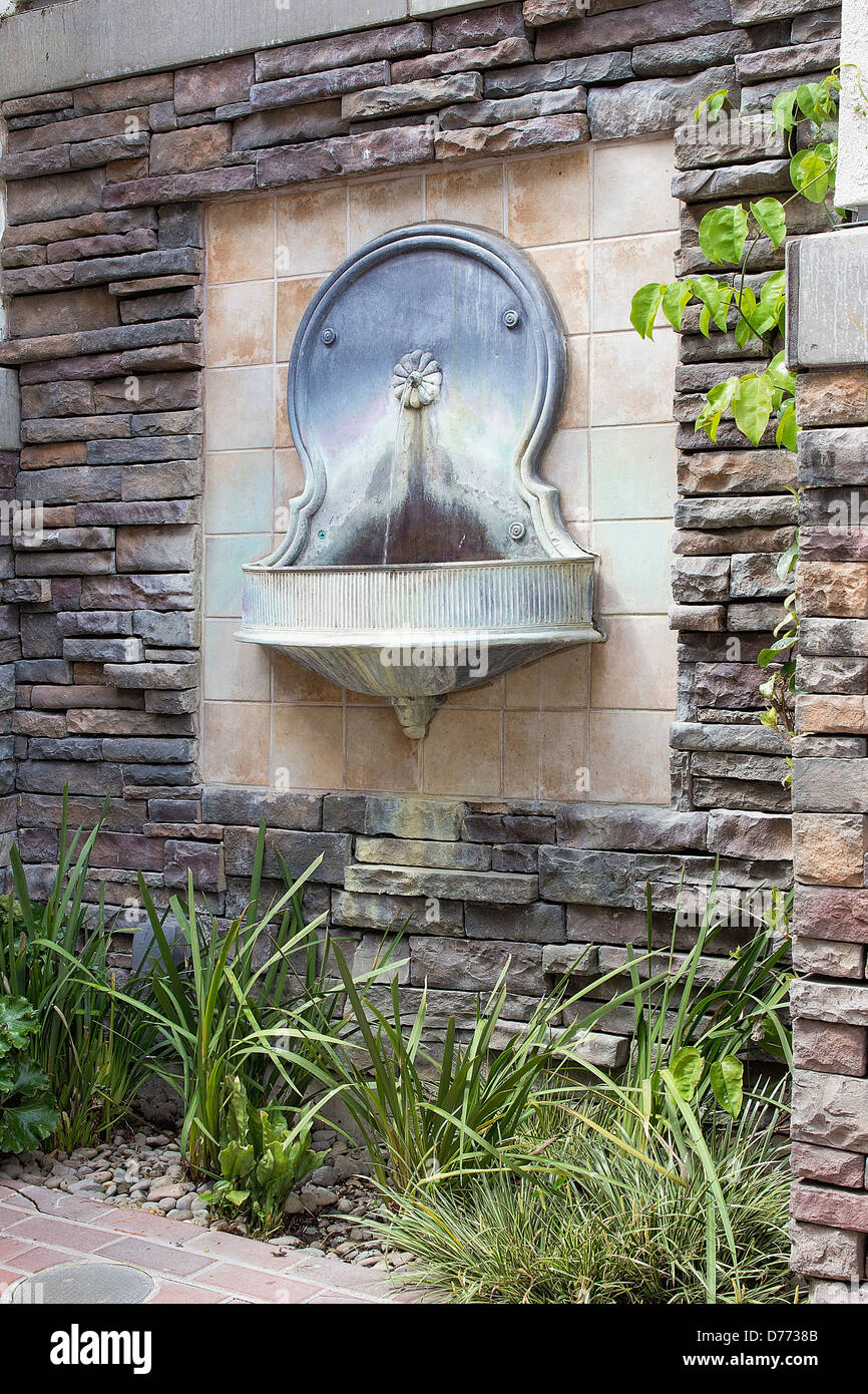 Toskanischen Stil Wandbrunnen Wasser auf formalen Garten im Innenhof mit Landschaftsbau Pflanzen Stockfoto