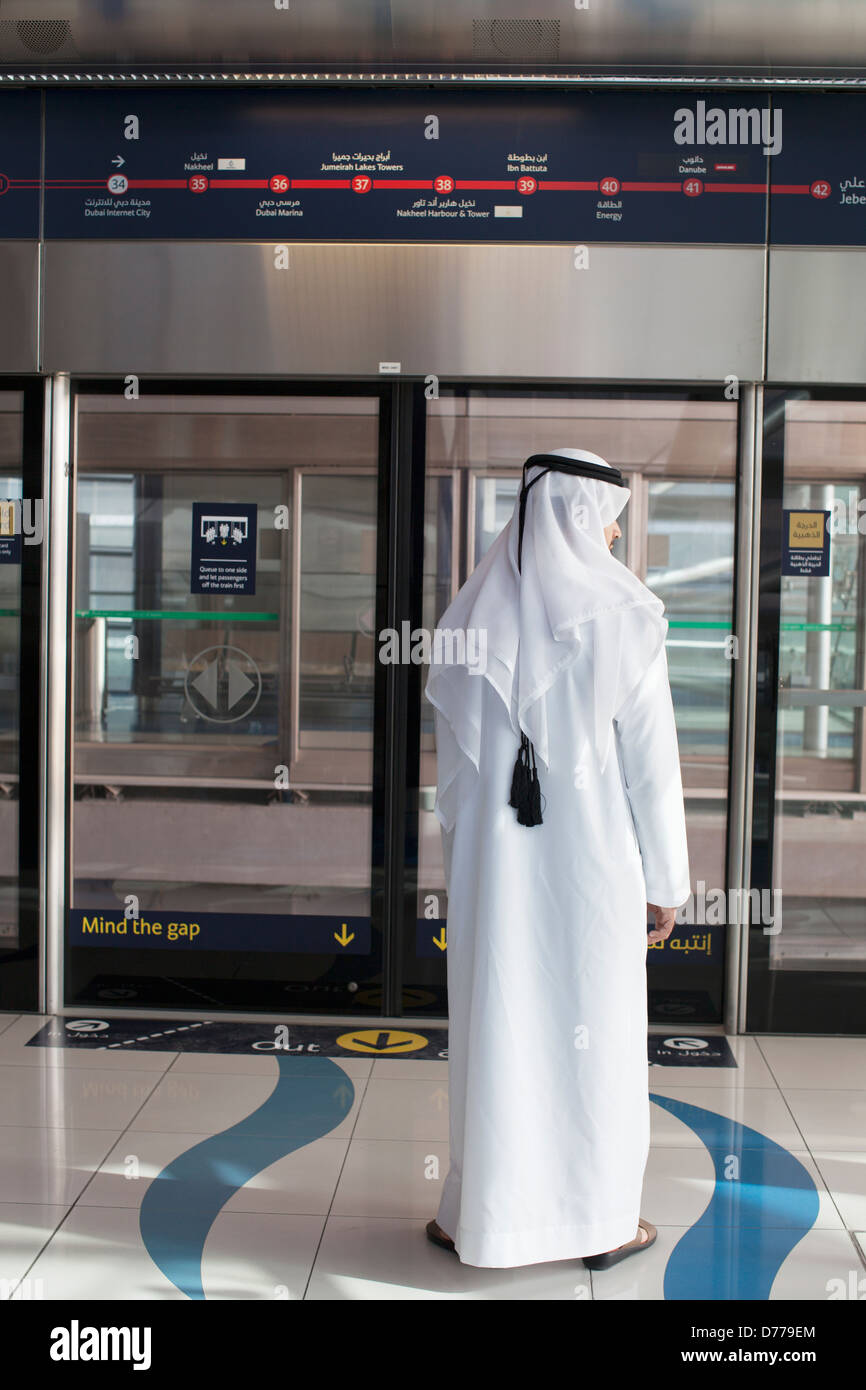 Arabische Mann in traditioneller Kleidung mit Metro in Dubai Stockfoto