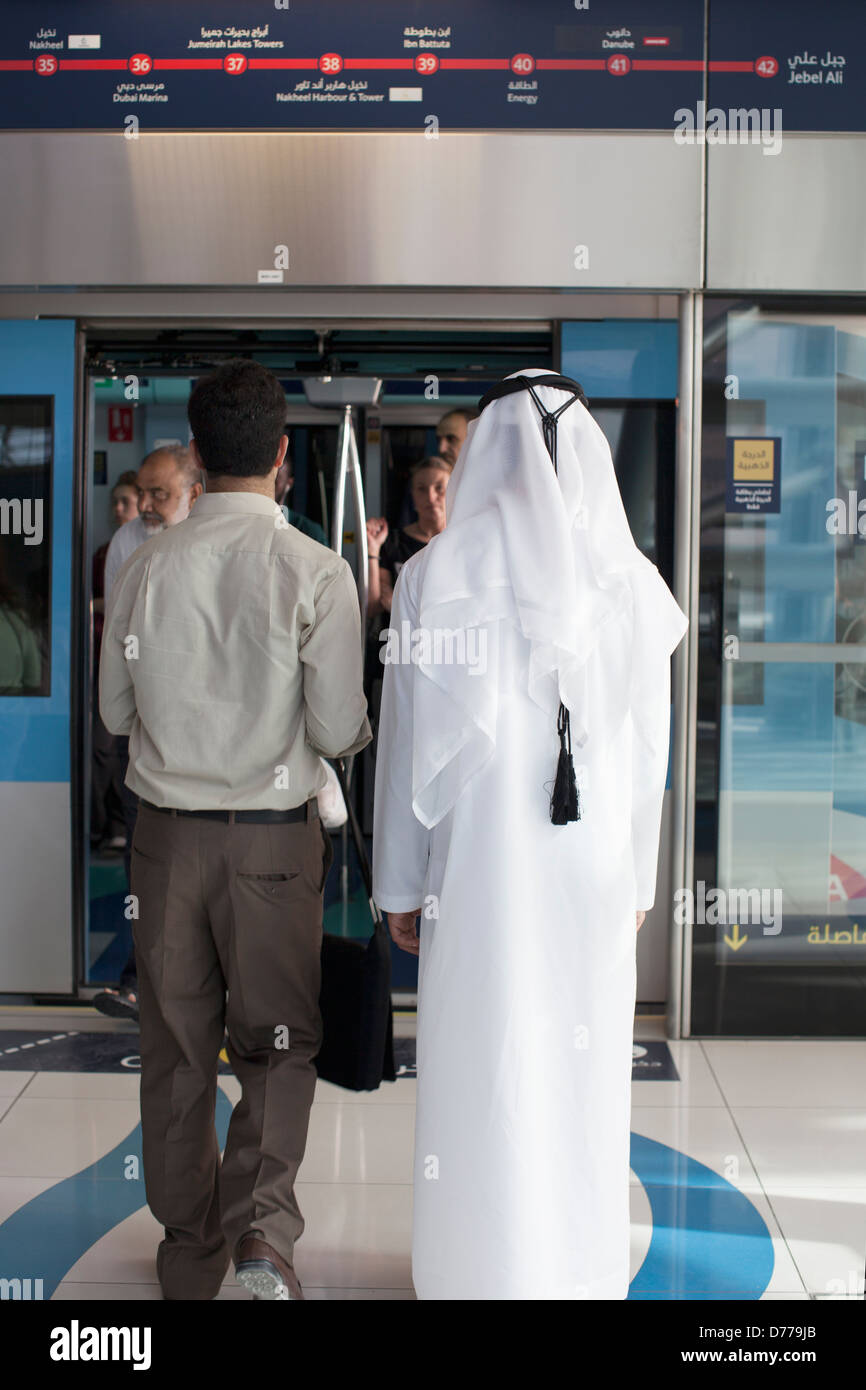 Arabische Mann in traditioneller Kleidung mit Metro in Dubai Stockfoto