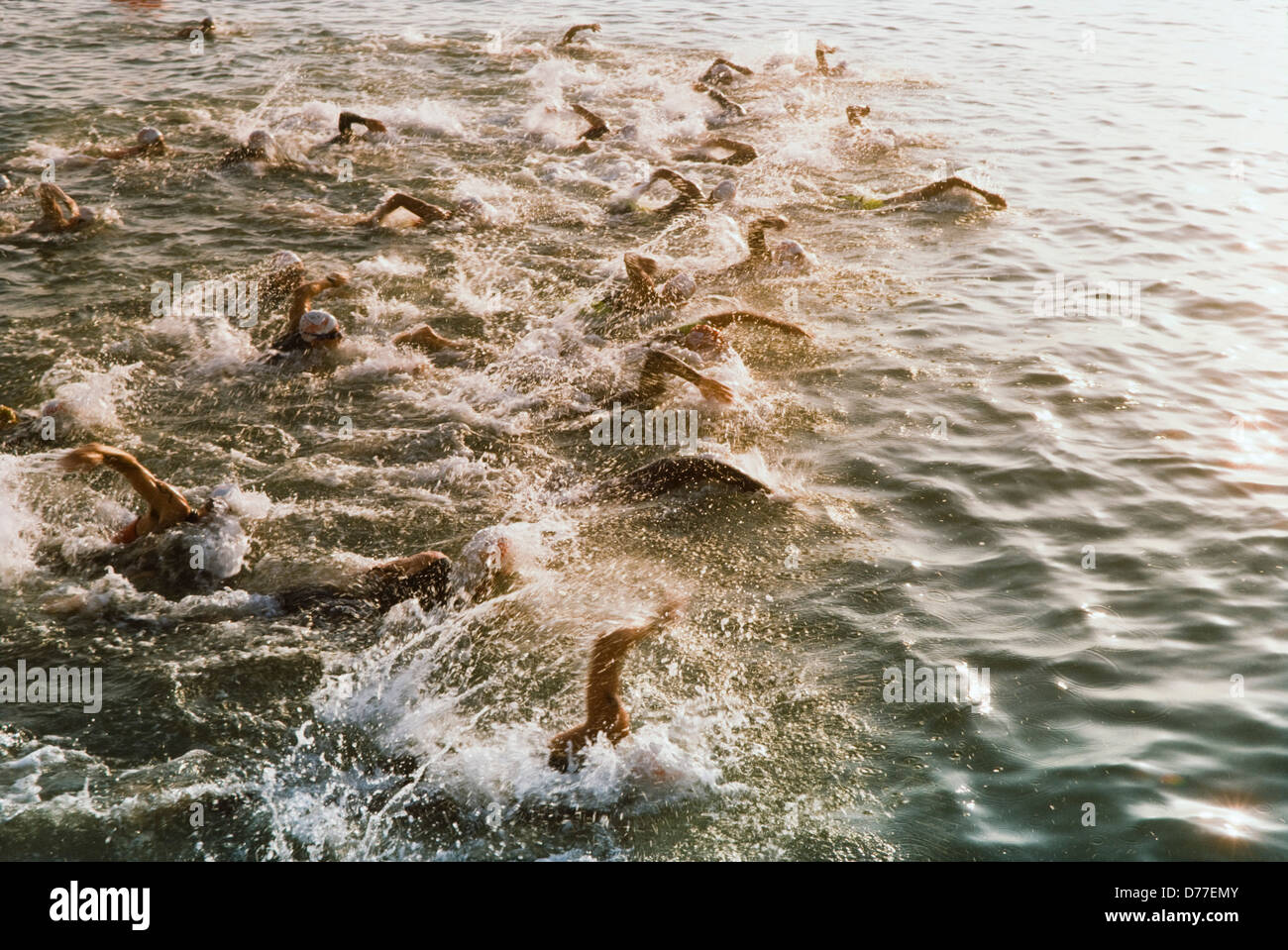 Start des Ironman Triatalon Konkurrenten Schwimmen im Ozean, Bewegungseffekte und Spritzen. Stockfoto