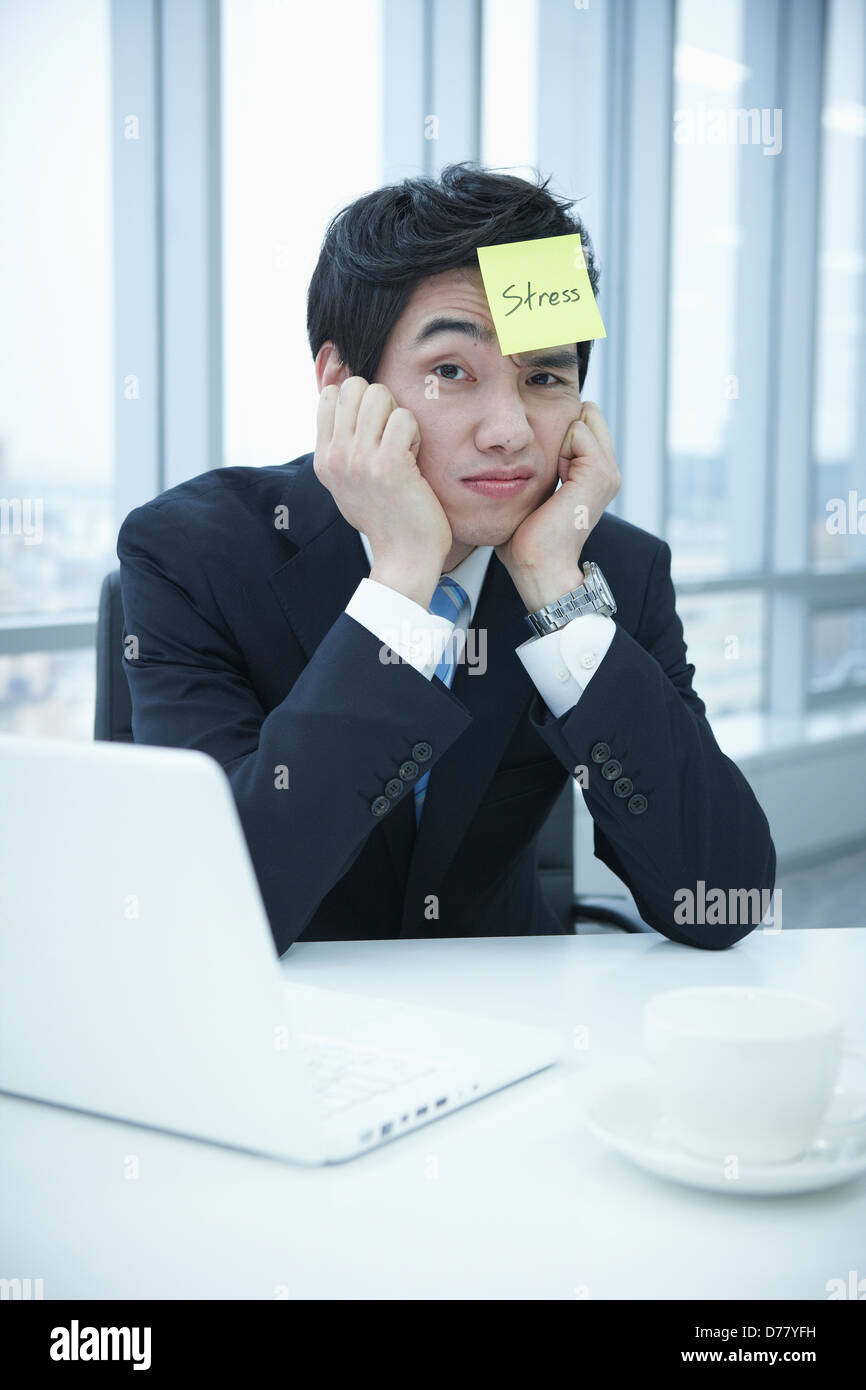 Geschäftsmann, sitzen auf einem Schreibtisch mit einem Beitrag auf seinem Kopf sagen stress Stockfoto