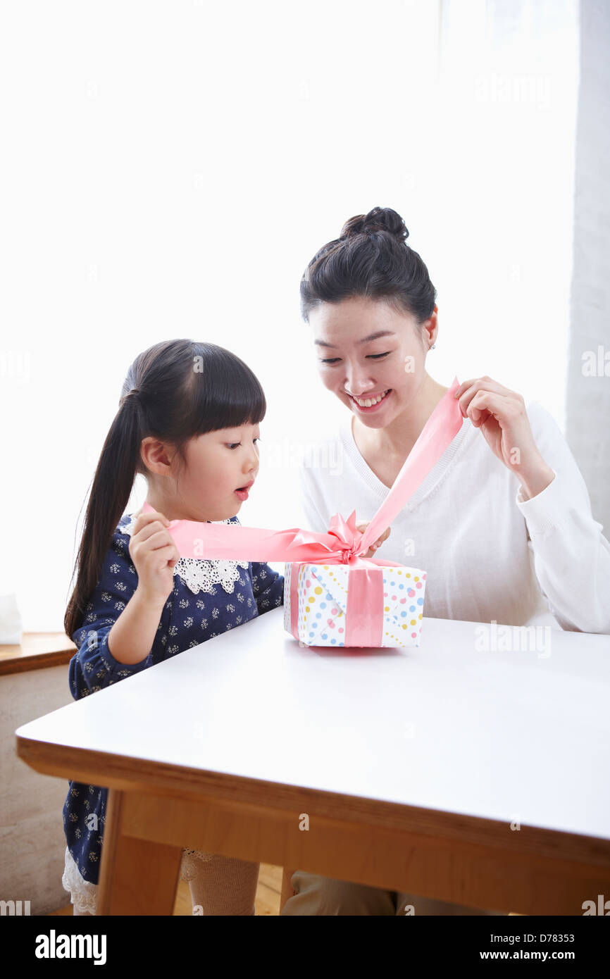 Mutter und Tochter ein Geschenk auf einem Tisch öffnen Stockfoto