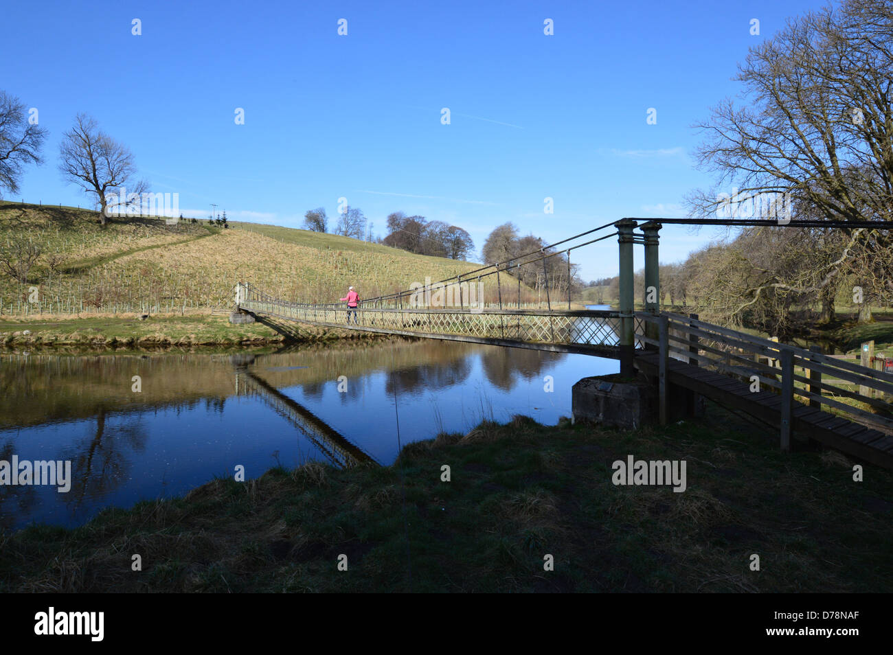 Frau, die über die Hängebrücke über den Fluss Wharfe in der Nähe von Hebden auf die Dales Weg lange Strecke Fußweg Yorkshire Stockfoto