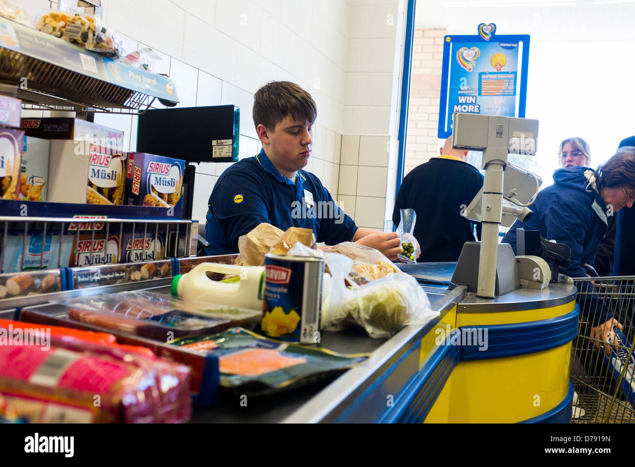 Ein junger Mann arbeitet an der Kasse bei Lidl-Supermarkt, UK Stockfoto