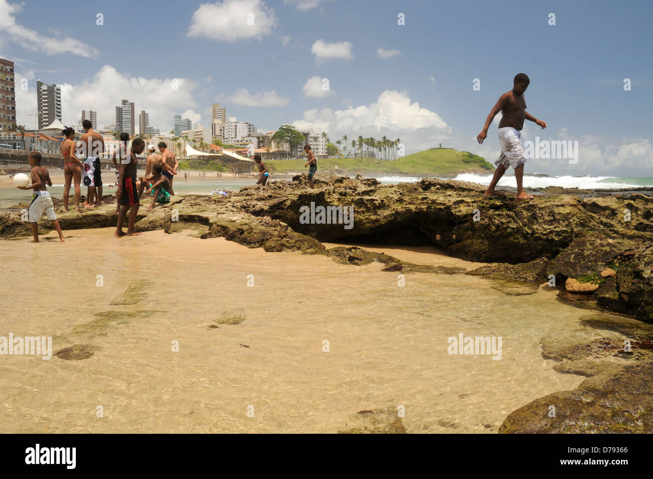 Badegäste am Strand von Barra mit Morro Cristo im Hintergrund Stockfoto