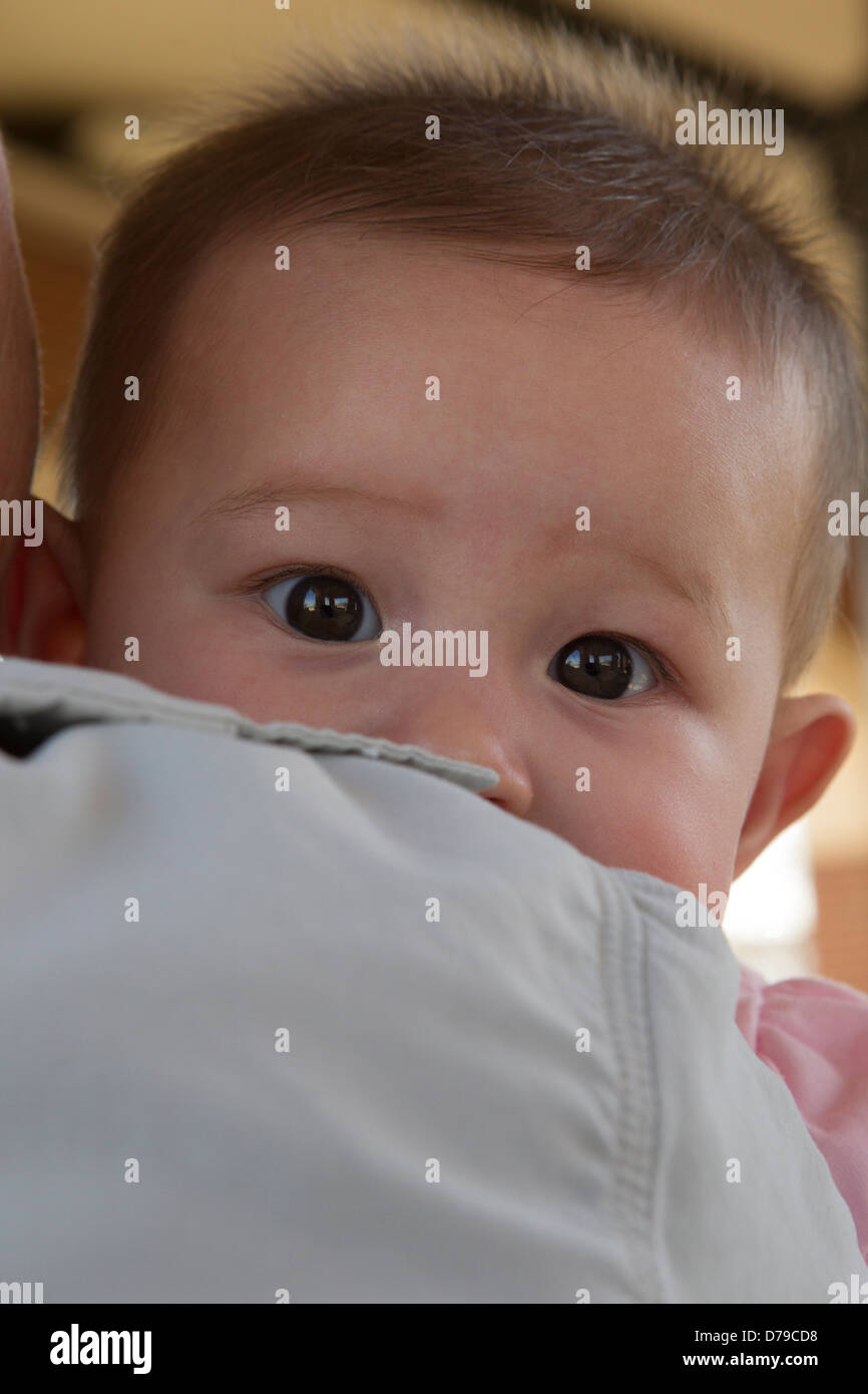 Ein fünf Monate altes Babymädchen blickt über die Schulter mit Besorgnis Stockfoto