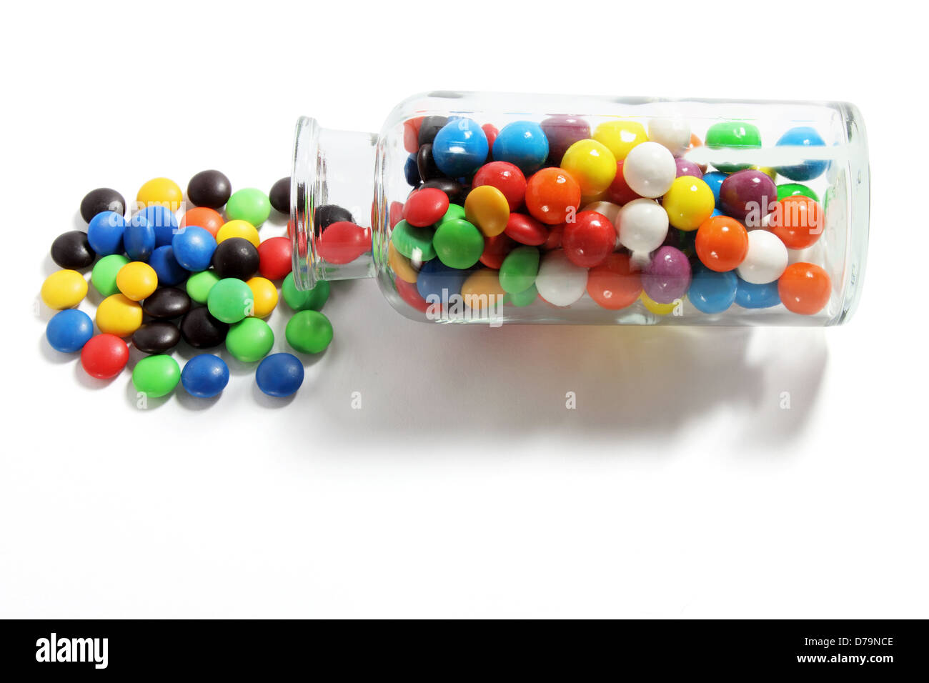 Glasflasche mit Schokolinsen Stockfoto