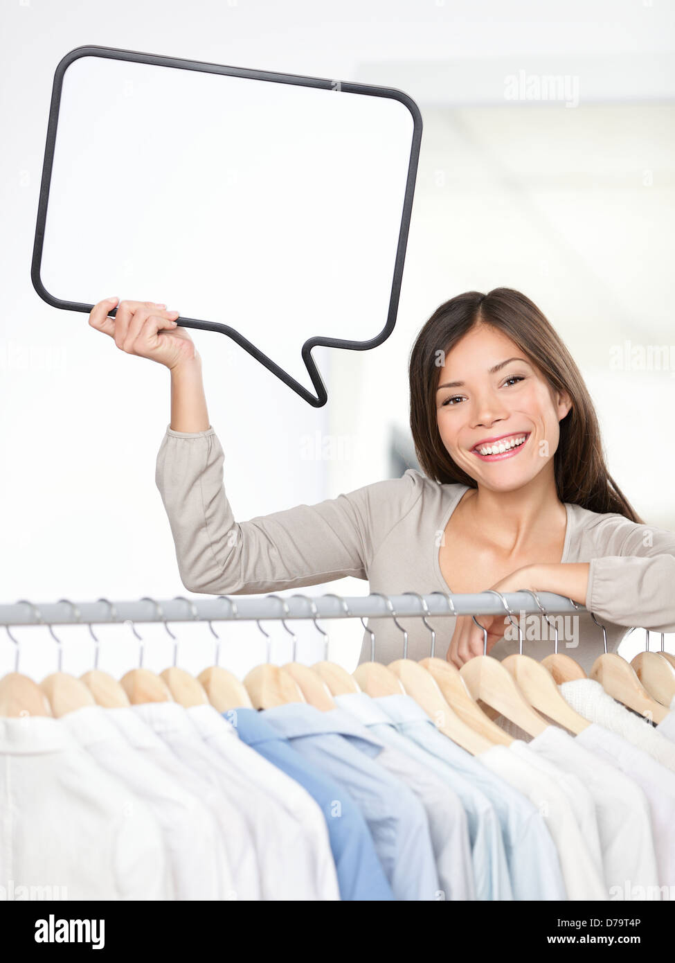 Shopping anmelden Frau in ein Bekleidungsgeschäft. Kleine Kleider Geschäft Inhaber mit Sprechblase Zeichen glücklich lächelnd hinter Wäscheständer. Schöne junge asiatische C Stockfoto