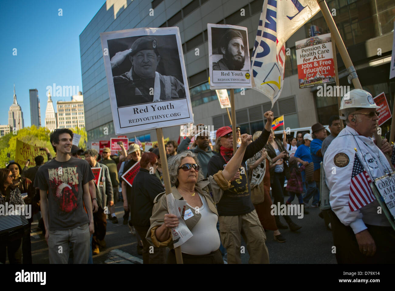 Mittwoch, 1. Mai 2013, New York, NY, USA: Arbeitnehmer Rechte Demonstranten, darunter auch eine Frau mit einem "Roten Jugend" Schild mit einem Bildnis von Hugo Chavez und ein Mann mit einem Schild mit Fidel Castros Bild, März auf Broadway in Richtung Rathaus nach einer Kundgebung in New York-Union Square zum International Workers Tag, auch bekannt als May Day. Stockfoto