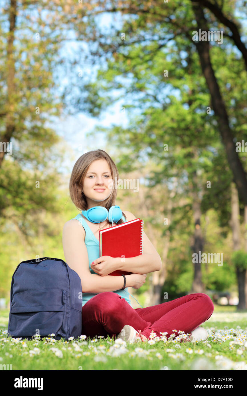 Studentin mit Notebook und Kopfhörer sitzen auf einer Wiese in einem park Stockfoto