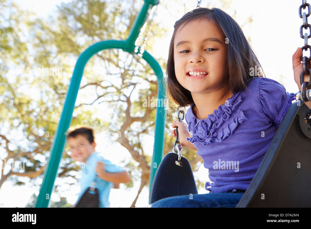 Jungen und Mädchen spielen auf Swing im Park Stockfoto