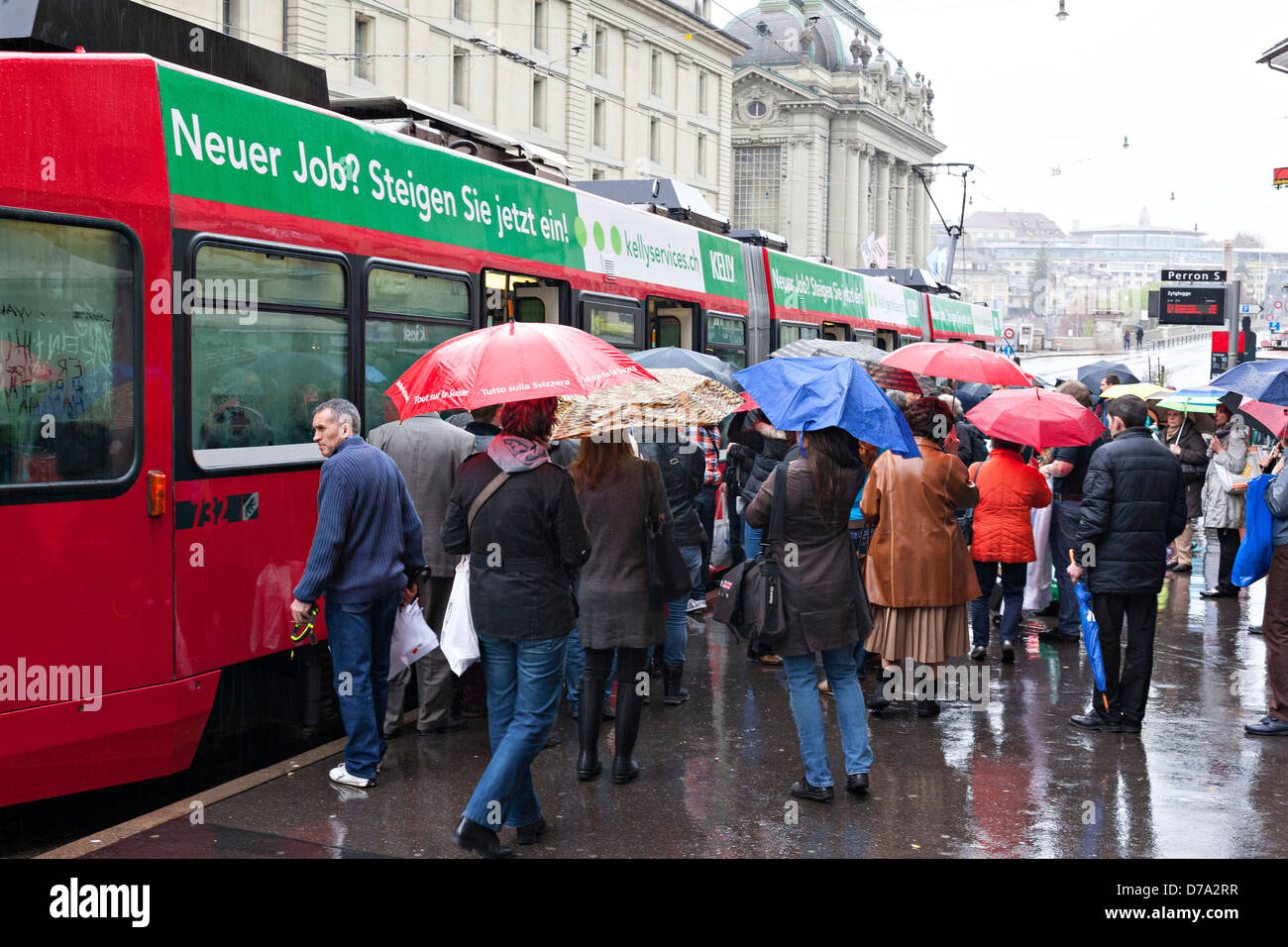 Menschen mit Regenschirmen einsteigen in eine Straßenbahn in Kornhausplatz, Bern Schweiz Stockfoto