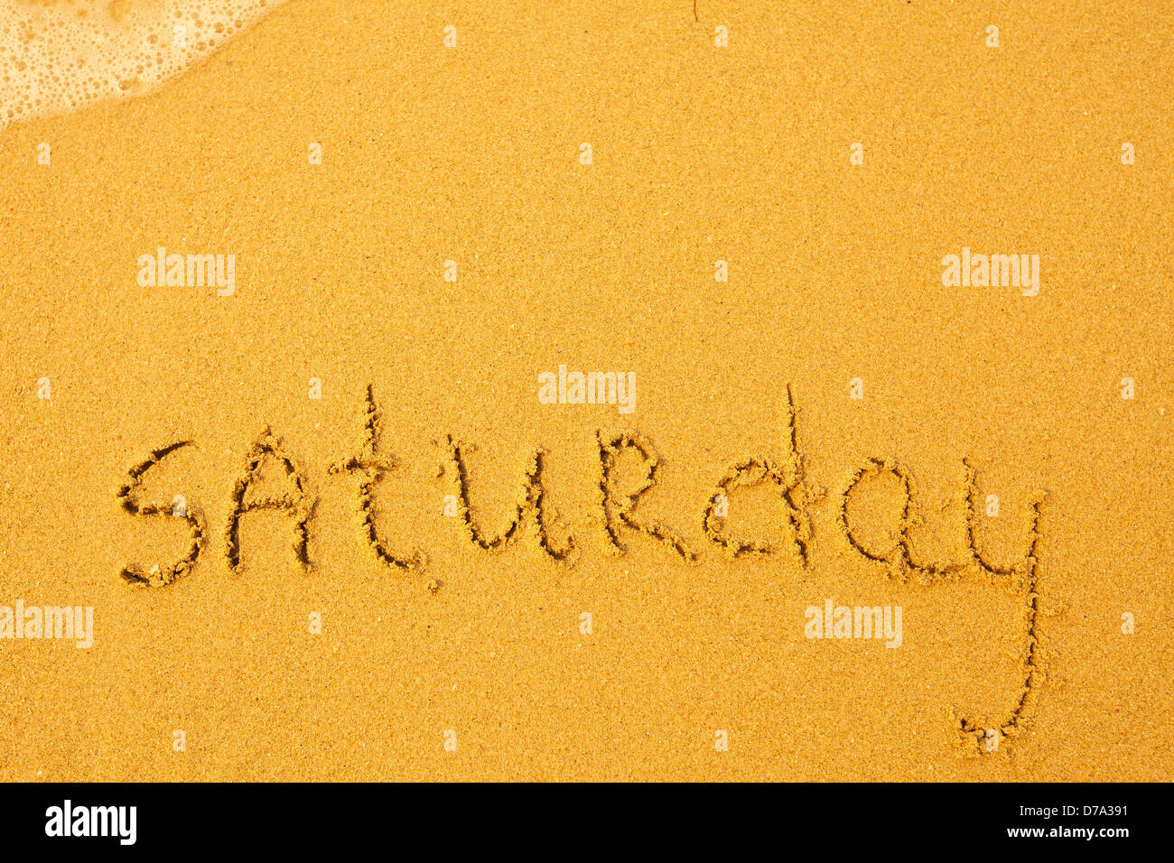 Samstag - geschrieben im Sand am Strand Textur. Stockfoto