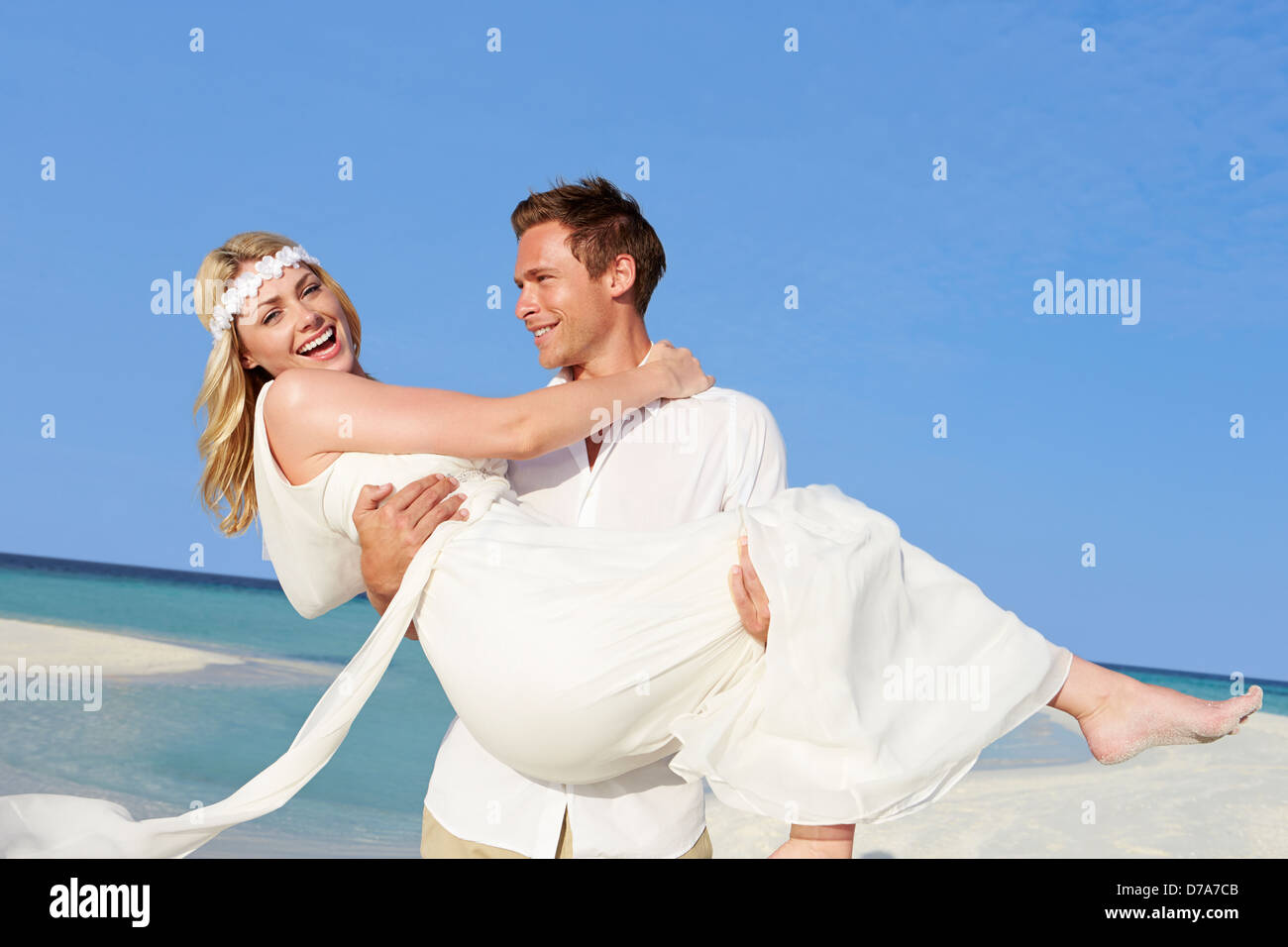 Bräutigam trägt Braut am schönen Strandhochzeit Stockfoto