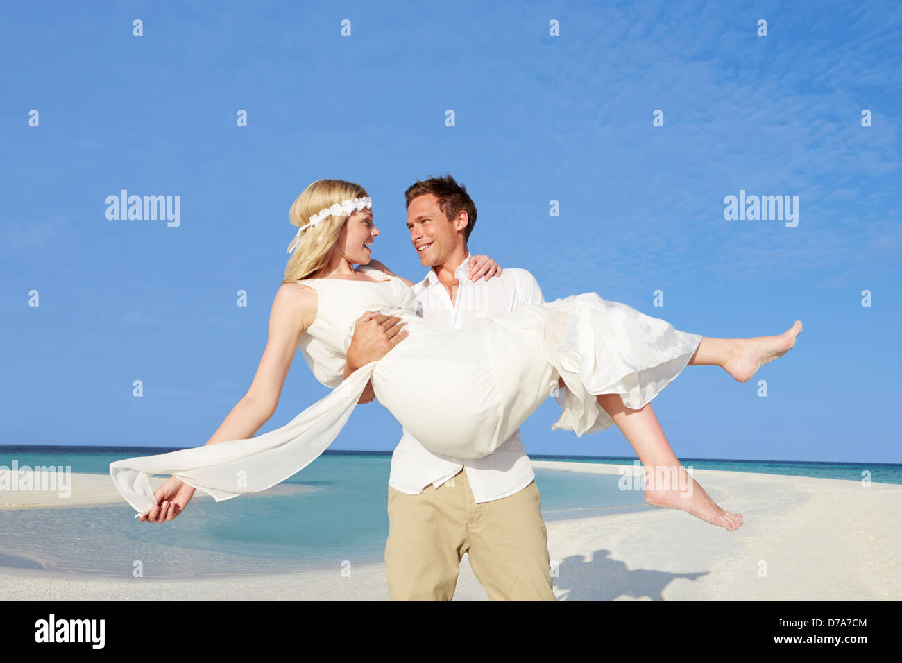 Bräutigam trägt Braut am schönen Strandhochzeit Stockfoto