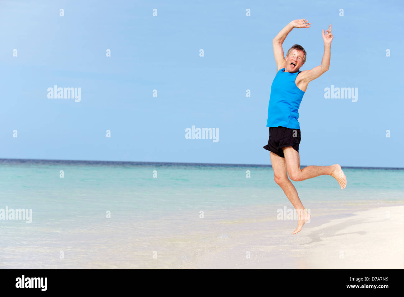 Ältere Mann springt am schönen Strand Stockfoto