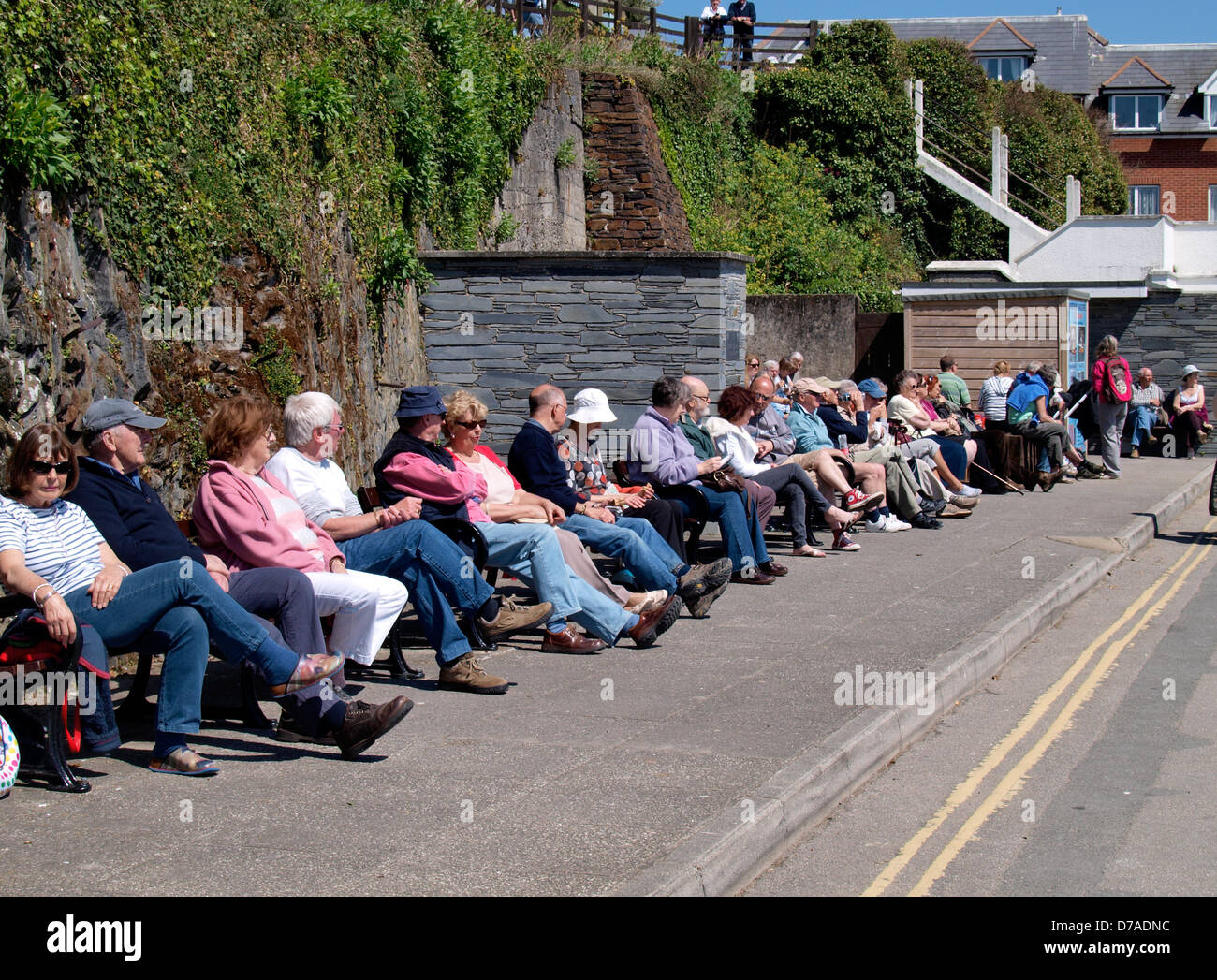 Reihe von Menschen saßen auf öffentlichen Bänke, Padstow, UK 2013 Stockfoto