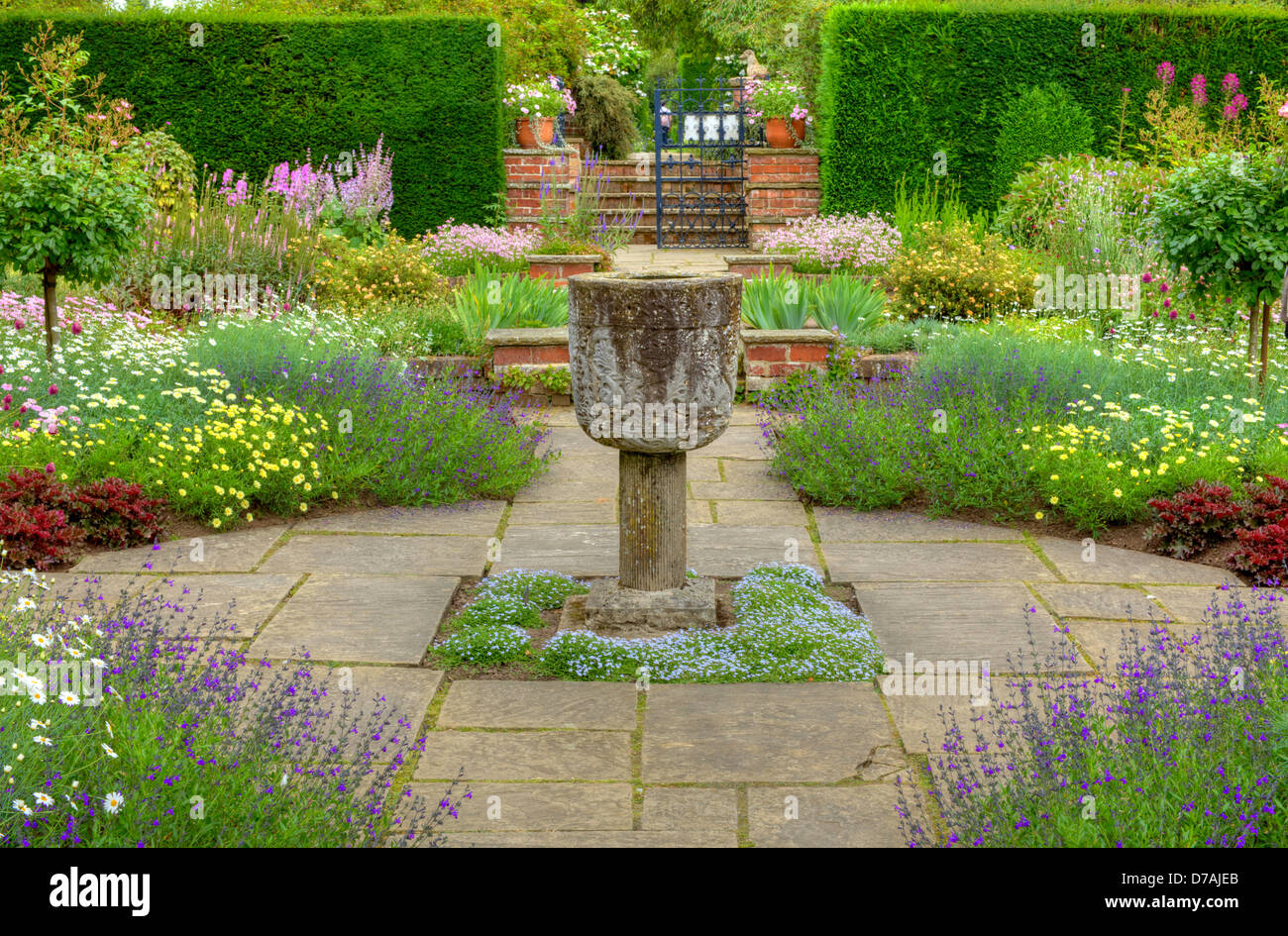 Gekennzeichnete Gartenanlage mit einem steinernen Vase Ornament und Sommer Blumen. Stockfoto