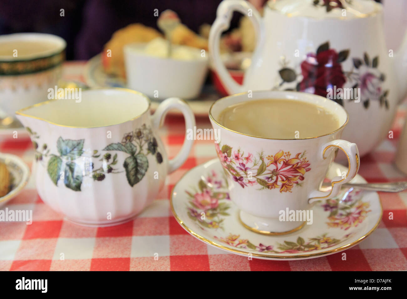 Der traditionelle englische Nachmittagstee mit blumigen China Teetasse mit Untertasse auf einer rot-weißen Tischdecke in einem Café. England Großbritannien Großbritannien Stockfoto