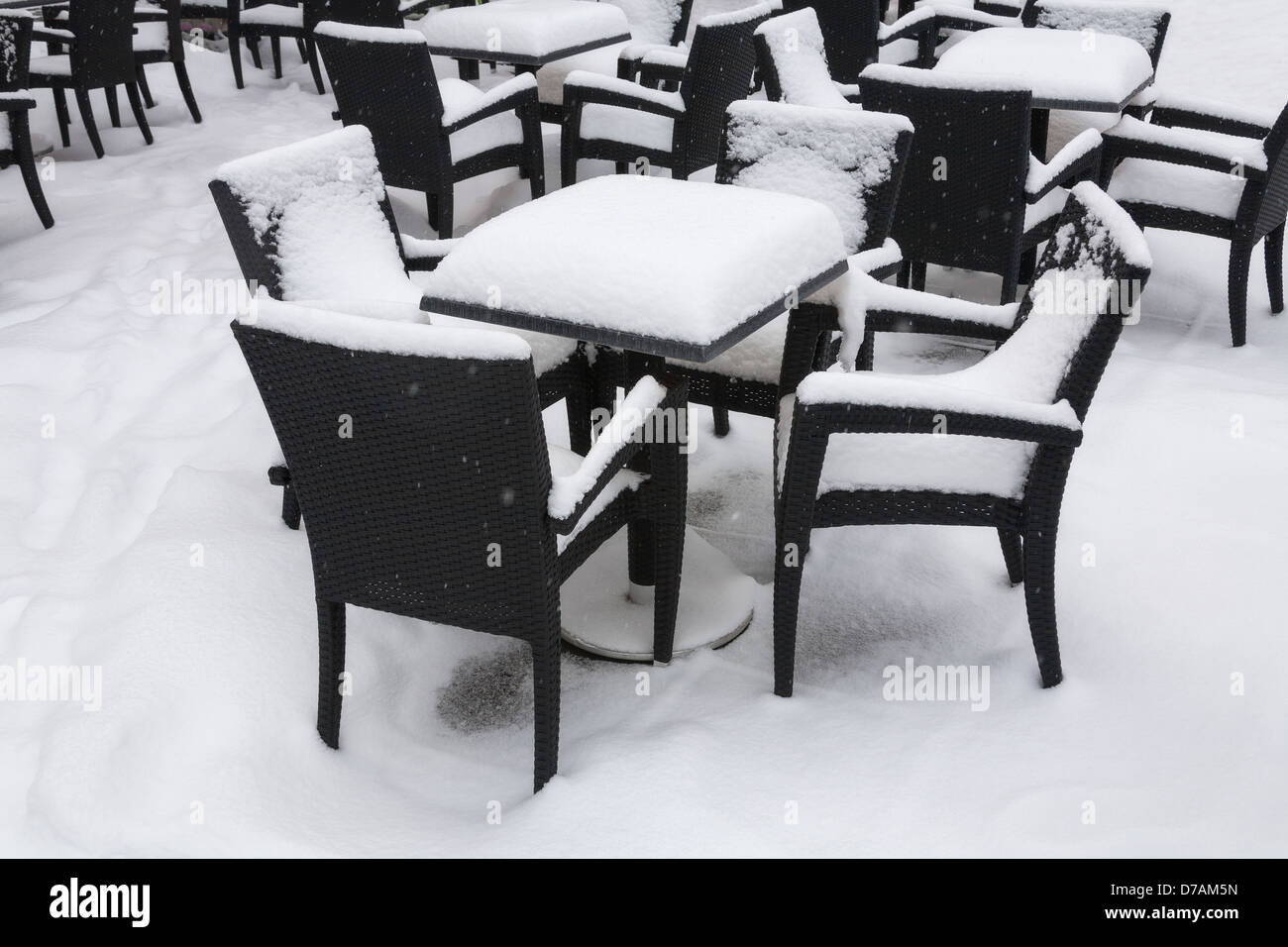 Stühle und Tische, die zu Beginn des Frühlings mit Schnee bedeckt Stockfoto