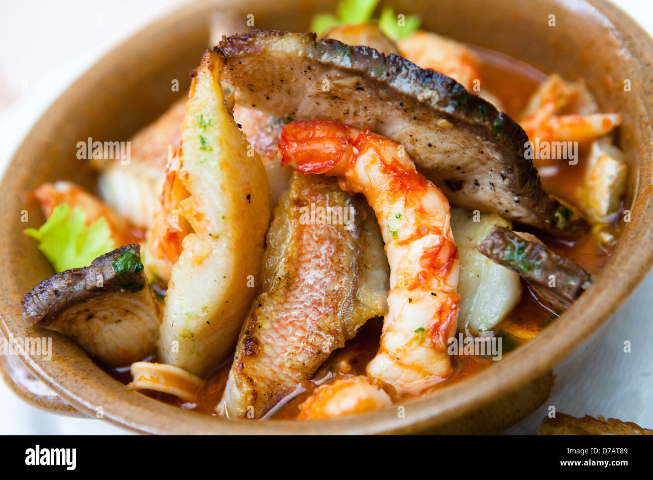 Fischsuppe mit Tomaten Sauce Basilikum Chili Schwertfisch Garnelen geröstetes Brot Knoblauch Zackenbarsch Filet Stockfoto