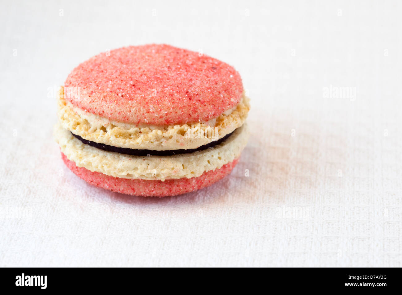 Makronen mit schwarzem Johannisbeeren-Violett-Geschmack auf einer weißen Tischdecke Stockfoto