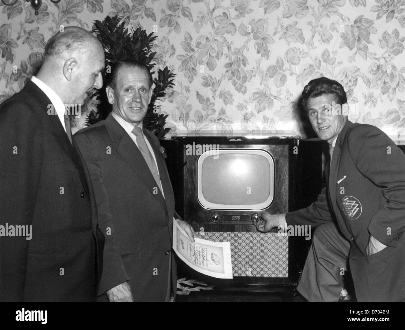 Sepp Herberger (M), Nationalspieler Hans Schäfer (r) und Inhaber der Firma Graetz (l) stehen neben einem TV am 19. Juli 1954. Deutsche Unternehmen hatte die zweiundzwanzig Nationalspieler und Trainer TV-Geräte als Geschenk gegeben. Sepp Herberger, deren Sprüche wie "Das Spiel dauert 90 Minuten" und "nach das Spiel ist vor dem Spiel" weithin wurden bekannt, war einer der wichtigsten Figuren des Nachkriegs-Deutschland. Er gab wieder eine unbestreitbar Stück Selbstvertrauen nach Deutschland mit dem Sieg der Weltmeisterschaft 1954 in Bern. Stockfoto