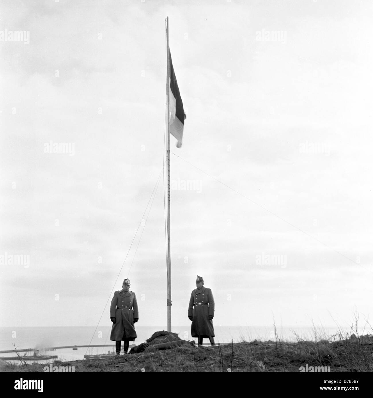 Zwei Polizisten halten Ehre Wache an der Flagge von Helgoland. Die Insel Helgoland wurde begangen zurück nach Deutschland durch die britische Regierung am 1. März 1952, nachdem es eine verbotene, Todeszone und eine Bombe Exerzierplatz der britischen Luftwaffe nach der Bombardierung im zweiten Weltkrieg wurde und eine schwere Strahlen. Stockfoto