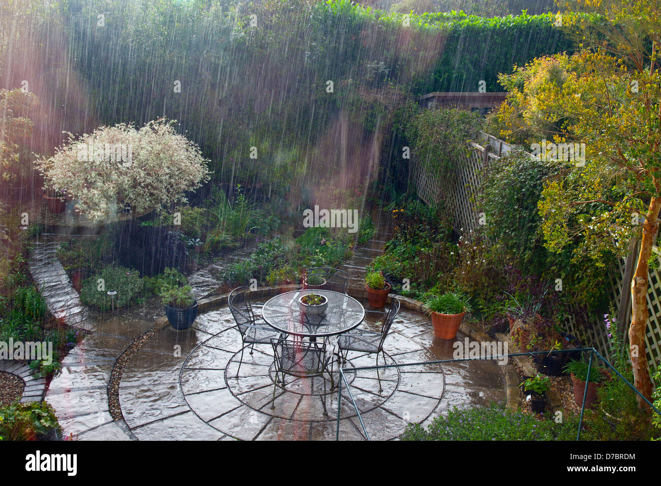 Ein Platzregen geht über einen Garten in dem Dorf Cossington, Somerset, England, UK Stockfoto