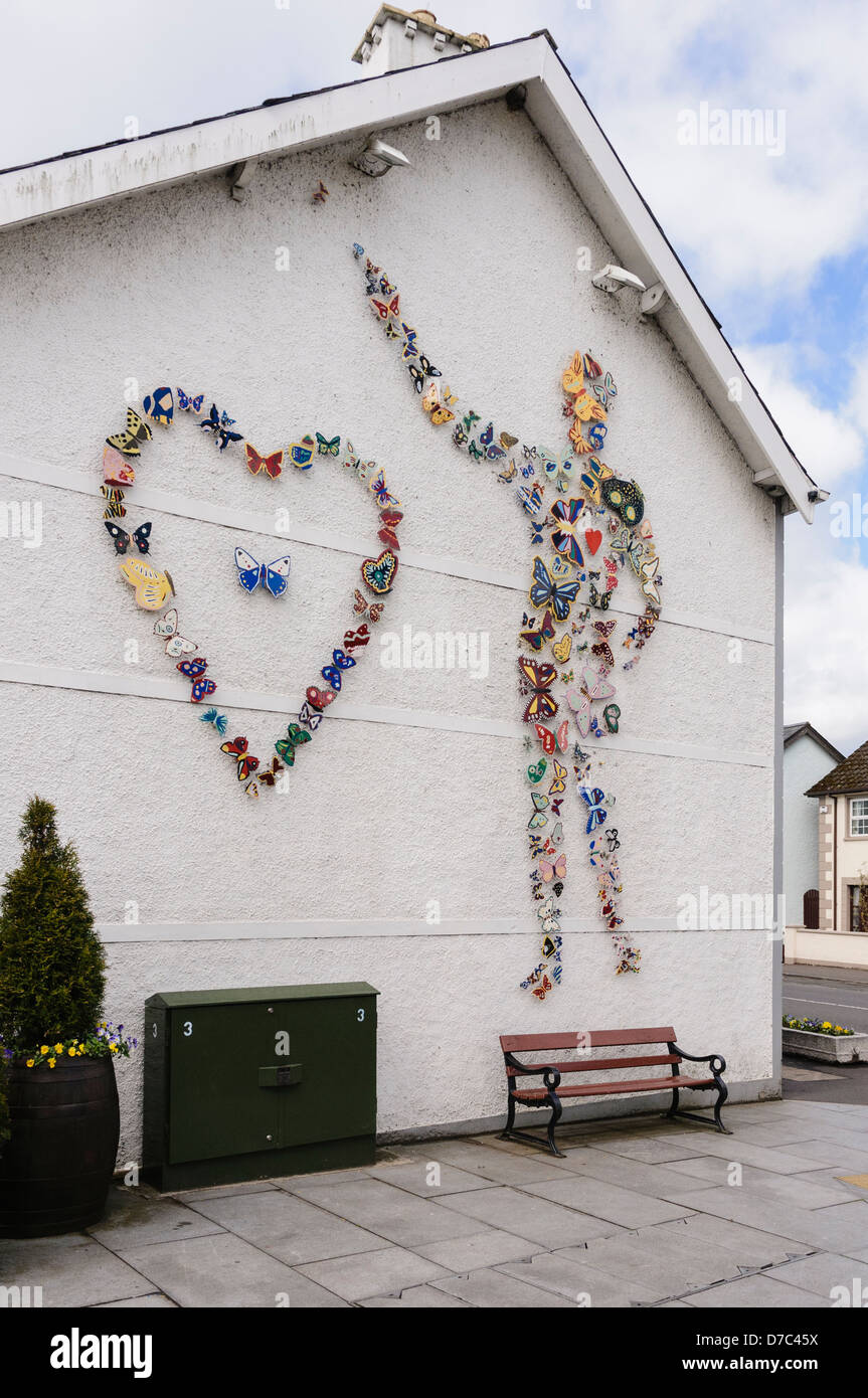 Keramik Schmetterlinge, der örtlichen Schule Kinder, die an der Wand in Broughshane Dorf bis eine Person und ein Herz. Stockfoto