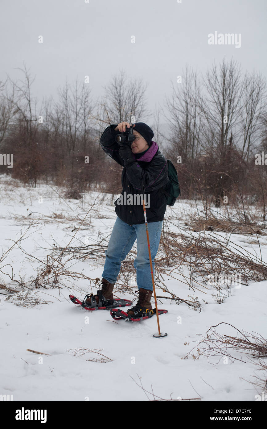 Eine Frau-Fotograf ist auf die Jagd auf Schneeschuhen an einem winterlichen Tag in den Berkshires, Massachusetts. Stockfoto