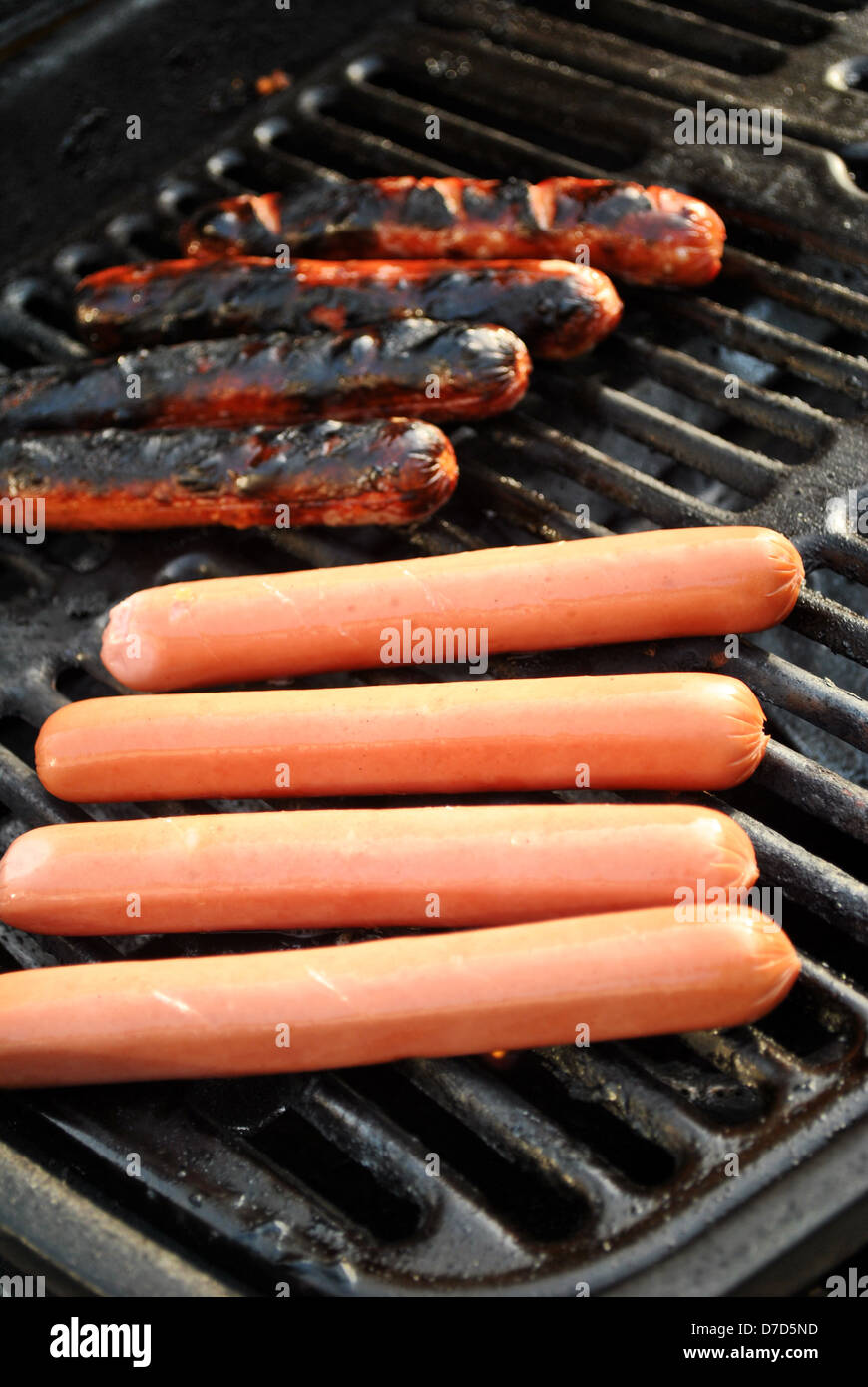 Gekocht und roh Hotdogs auf ein Picknick Grill Stockfoto