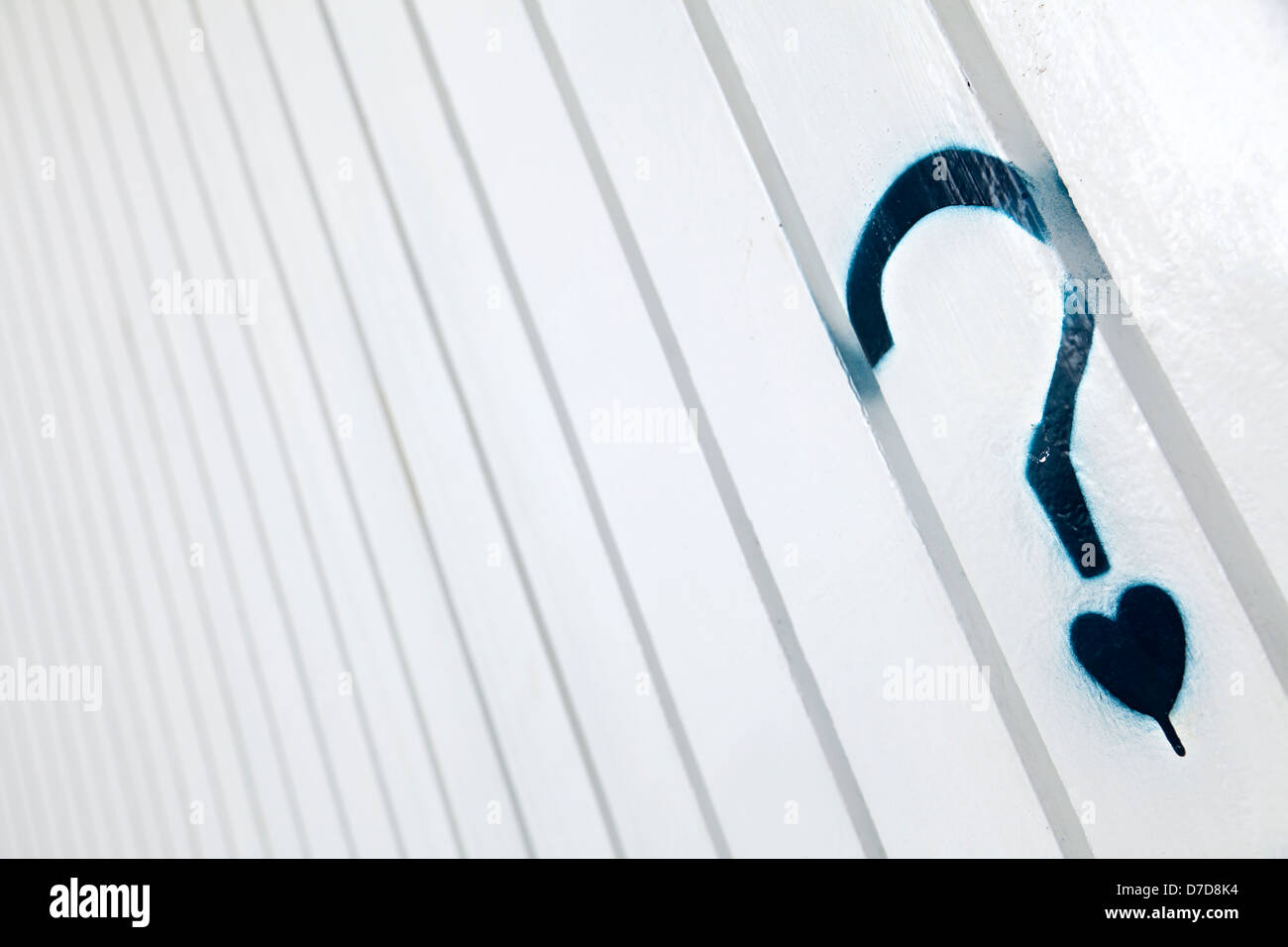 Eine blaue Grafitti in Form Fragezeichen kleines Herz Punkt stattdessen auf Weißmetall Wand Falten Muster. Stockfoto