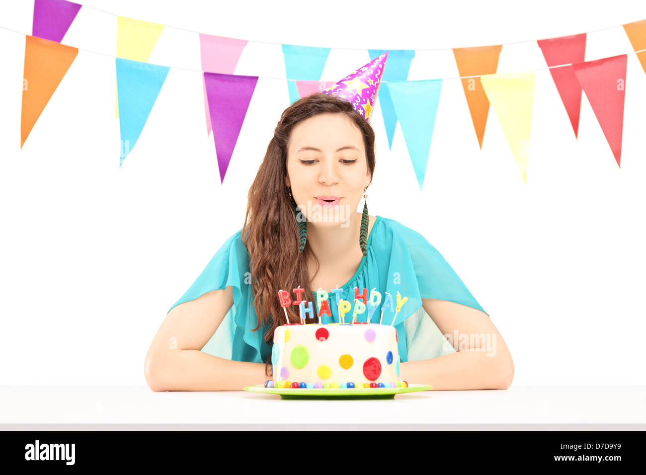 Ein Lächeln auf den Lippen Geburtstag Weibchen mit einen Partyhut bläst die Kerzen an ihrem Geburtstag Kuchen auf weißen Hintergrund isoliert Stockfoto