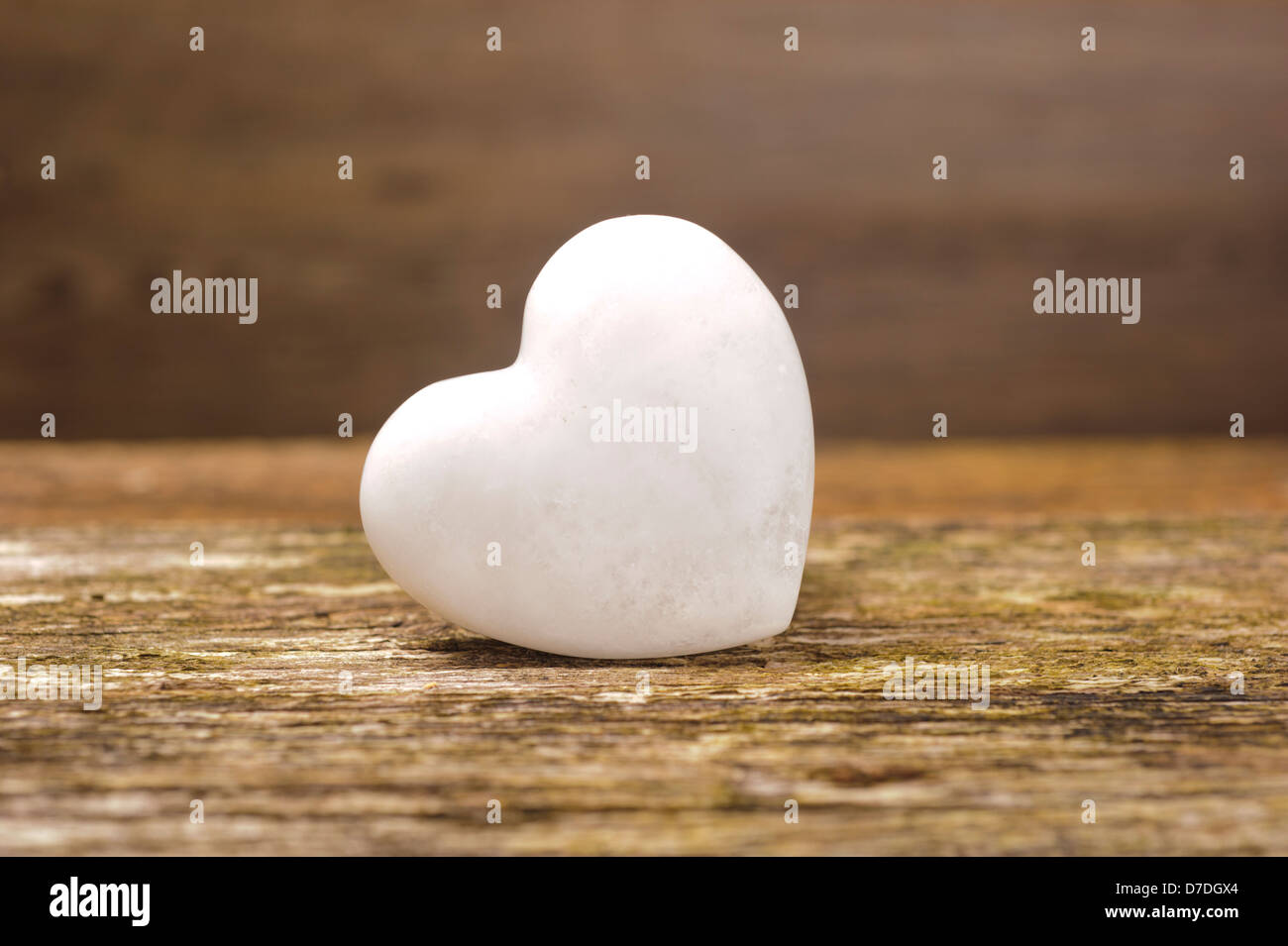 Weißes Herz aus Stein auf Holz Stockfoto