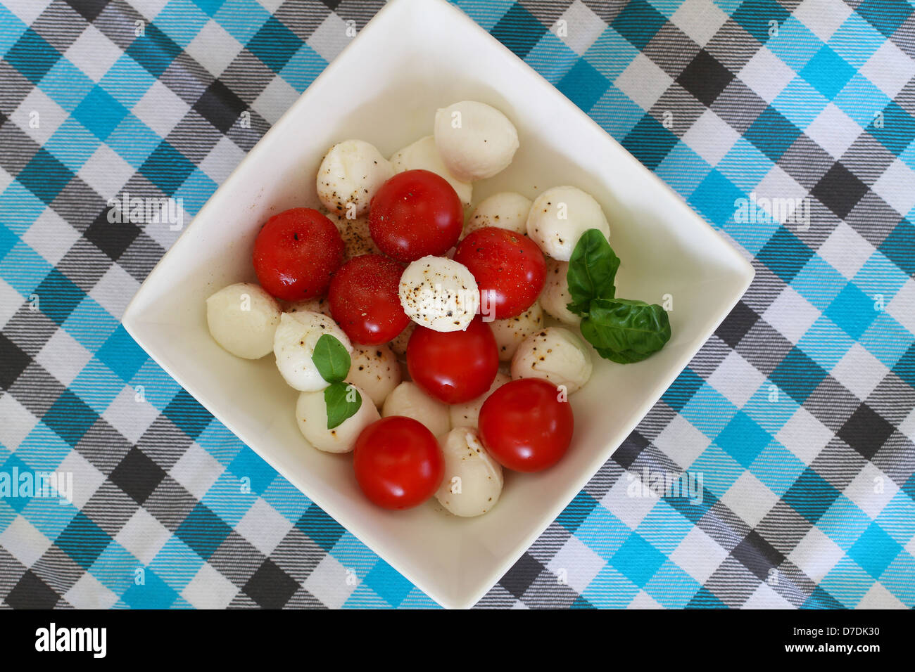 Mozzarella-Salat in Schüssel auf karierten Tischdecke weiß Stockfoto